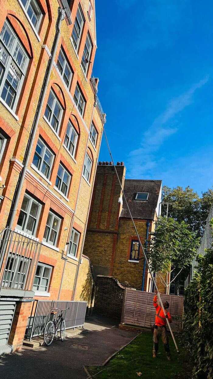 Window cleaner reaching upper windows on a red-brick building