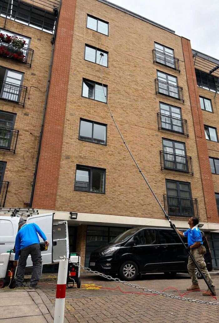 Window cleaner reaching windows on a modern white and glass building