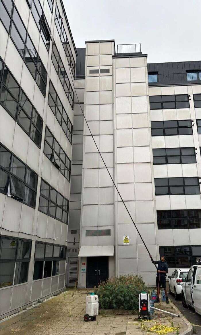 Window cleaner using a long pole between brick buildings