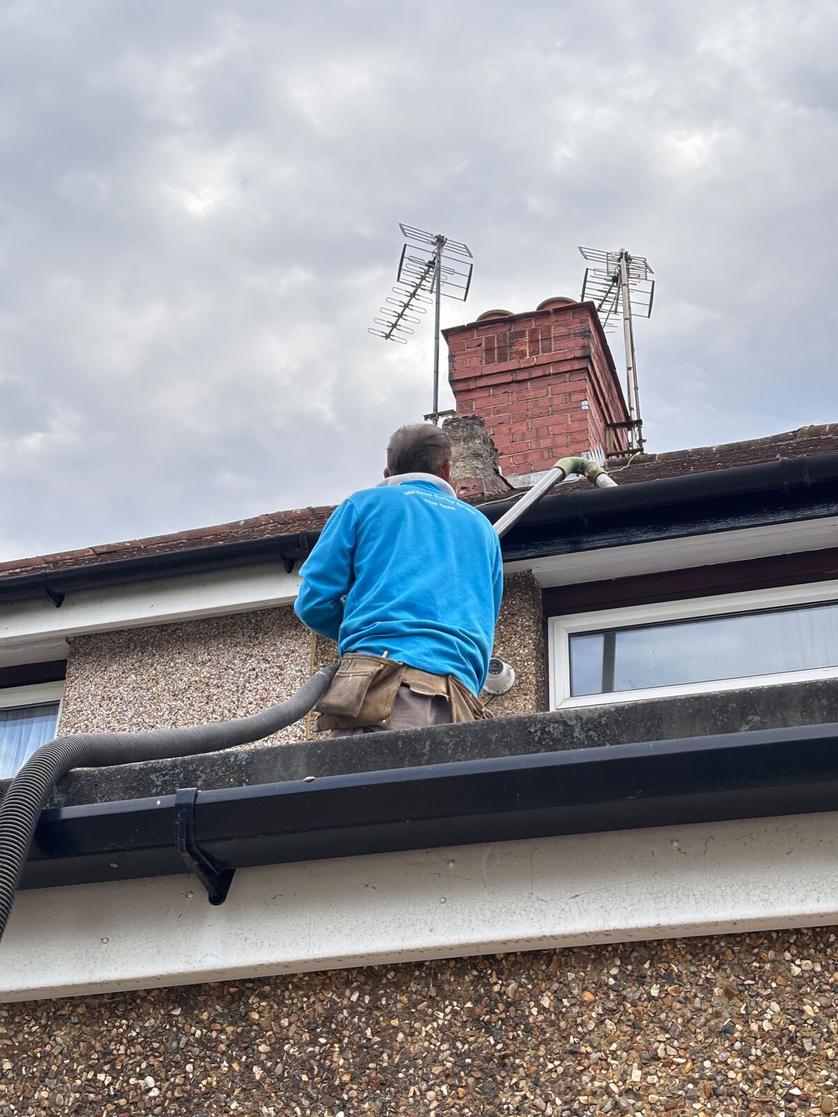 Gutter clearing from ground level using a pole-mounted vacuum system on a residential property
